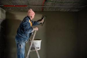 Travailleur plâtrant le mur de béton photo