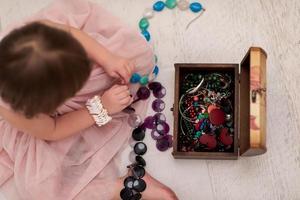 petite fille s'amusant en jouant avec les bijoux de sa mère photo