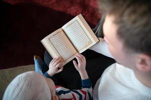 prière musulmane père et fils dans la mosquée priant et lisant le livre de houx coran ensemble concept d'éducation islamique photo