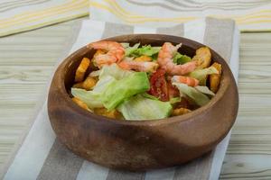 salade césar aux crevettes dans un bol sur fond de bois photo