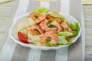 salade césar aux crevettes dans un bol sur fond de bois photo