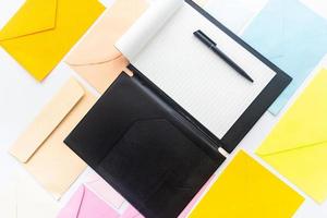 presse-papiers avec un stylo noir sur la couleur des enveloppes pastels. photo