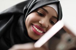 une fille afro utilise un téléphone portable et navigue sur les réseaux sociaux pendant une pandémie photo