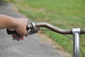 un jeune homme tient des guidons de vélo vintage qui se sont garés sur le fond de la prairie, une mise au point douce et sélective à portée de main. photo