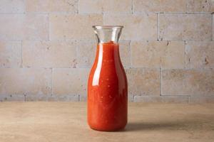 une bouteille de bocal en verre avec de la sauce tomate maison se dresse sur la table. photo