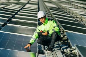 le portrait d'un jeune ingénieur vérifie les panneaux solaires photovoltaïques. concept. service d'électricité de technologie d'énergie renouvelable, énergie verte. photo