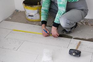 travailleur installant les carreaux en céramique effet bois sur le sol photo