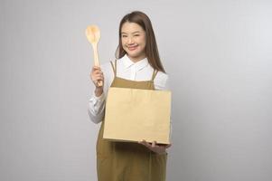 portrait de jeune femme asiatique portant un tablier sur fond blanc studio, cuisine et concept d'entrepreneur photo