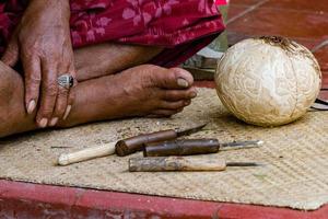 mains travaillant et sculptant le bois de coco en gros plan photo