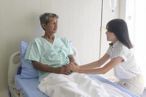 jeune fille rendant visite à un vieux père malade à l'hôpital, aux soins de santé et au concept médical photo