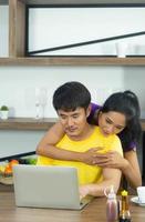 famille heureuse et drôle. beau couple asiatique, belle femme et bel homme prend son petit déjeuner, parle dans la cuisine photo