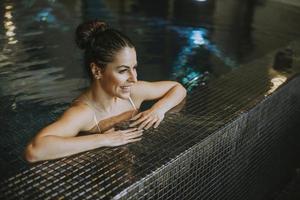 jeune femme se reposant au bord de la piscine intérieure photo