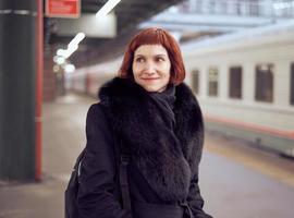 gare. belle fille est debout sur la plate-forme et attend le train. la femme voyage léger photo