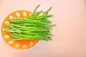 asperges - légume. asperges fraîches. asperges vertes marinées. grappes d'asperges vertes dans le panier sur fond orange calme, vue de dessus- image. photo