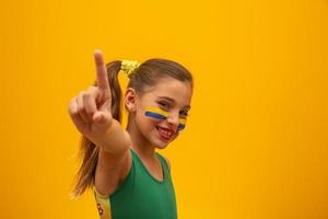 supporter de football, équipe du brésil. Coupe du monde. belle petite fille acclamant son équipe sur fond jaune photo