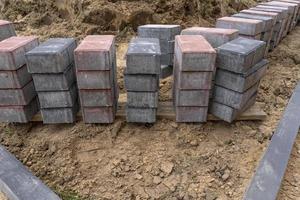 pose de dalles en béton gris dans le patio de l'allée de la cour de la maison. les maçons professionnels installent de nouvelles tuiles ou dalles pour l'allée, le trottoir ou le patio sur une fondation sablonneuse plate. photo