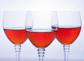 trois verres à vin transparents avec du vin rosé.