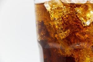 verre de cola avec de la glace de cola écrasée sur fond blanc dans du verre et il y a des gouttelettes d'eau autour. boisson fraîche noire fraîche. photo