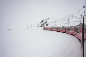 train rouge dans la neige dans les alpes suisses photo