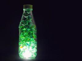 gros plan de billes de verre à l'intérieur d'une bouteille avec une lumière sur un fond sombre photo