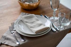 Cadre de table romantique festif avec argenterie, serviette grise et vaisselle blanche sur nappe de soie beige photo