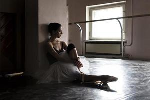 une charmante ballerine en body pose des éléments de ballet dans une coiffe dans un studio photo