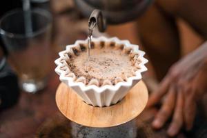 café goutte à goutte, barista versant de l'eau sur du café moulu avec filtre photo