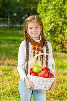 petite fille tenant un panier de pommes photo