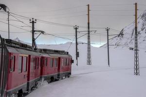 train rouge dans la neige dans les alpes suisses photo