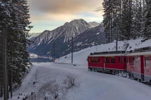 train rouge dans la neige dans les alpes suisses photo