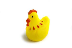 Tout-petit jouet poulet en caoutchouc jaune jouant dans la baignoire isolé sur blanc photo