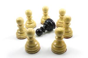 un groupe de pions d'échecs blancs forme un cercle au milieu il y a un noir photo