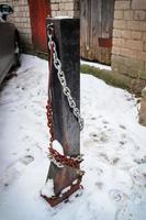 poste de stationnement avec des chaînes en acier utilisées pour fermer le parking debout dans une cour couverte de neige à l'extérieur photo