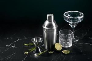 shaker à cocktail et verres à cocktail, et ingrédients sur fond de marbre foncé photo