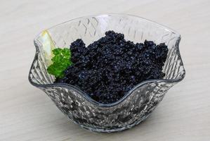 caviar noir dans un bol sur fond de bois photo