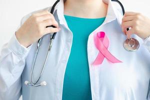 femme médecin en uniforme médical blanc avec ruban rose. Mois de la sensibilisation au cancer du sein. concept de soins de santé des femmes. symbole d'espoir et de soutien. photo