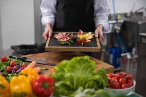 femme chef tenant une assiette de steak de boeuf photo