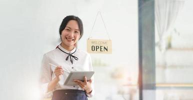 startup réussie propriétaire de petite entreprise PME beauté fille stand avec tablette smartphone dans un café-restaurant. portrait d'une femme asiatique bronzée propriétaire d'un café barista. PME entrepreneur vendeur concept d'entreprise photo