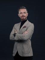 portrait d'un homme d'affaires senior élégant et élégant avec une barbe et des vêtements d'affaires décontractés en studio photo isolé sur fond sombre gesticulant avec les mains