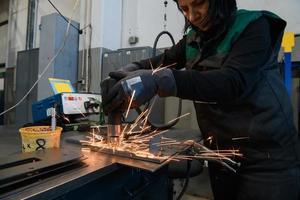 une femme travaillant dans l'industrie moderne de la production et de la transformation des métaux soude le produit et le prépare pour une machine cnc photo