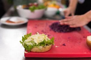 mains de chef coupant la salade pour le burger photo