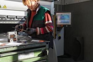 femme travaillant dans une usine moderne et préparant des matériaux pour une machine cnc. photo