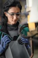 une travailleuse portant des lunettes de sécurité contrôle la machine de tour pour percer les composants. tour à métaux usine de fabrication industrielle photo