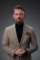 portrait d'un homme d'affaires senior élégant et élégant avec une barbe et des vêtements d'affaires décontractés en studio photo isolé sur fond sombre gesticulant avec les mains