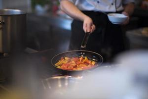 chef retournant les légumes au wok photo