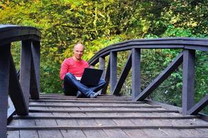 jeune homme d'affaires en chemise rouge au pont travaillant sur un ordinateur portable photo