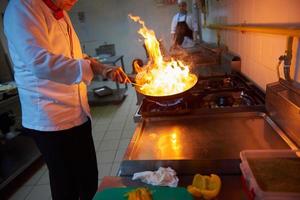 le chef de la cuisine de l'hôtel prépare la nourriture avec le feu photo