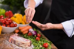 chef mettant du sel sur une tranche juteuse de steak cru photo