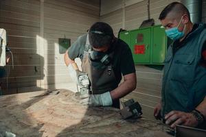 travail industriel pendant une pandémie. deux hommes travaillent dans une usine de métaux lourds, portant un masque sur le visage en raison d'une pandémie de coronavirus photo