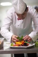 chef dans la cuisine de l'hôtel préparant et décorant la nourriture photo